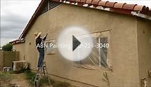 Spray painting and back rolling exterior of a stucco house.